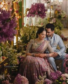 a man and woman sitting next to each other in front of flowers