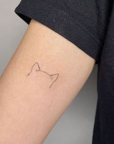 a woman's arm with a small cat tattoo on the left side of her arm