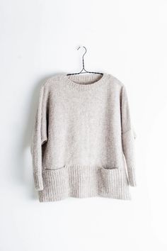 a sweater hanging on a hanger against a white wall with the top half turned down