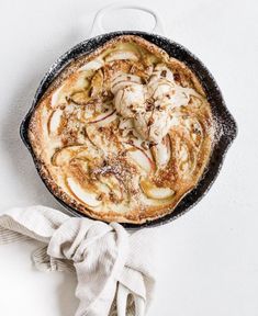 a skillet filled with food sitting on top of a white table next to a napkin