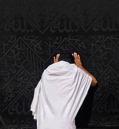 a man with his head covered by a white cloth standing in front of a black wall