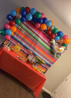 a table topped with balloons and cake next to a wall