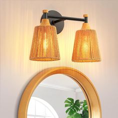 a bathroom with a mirror and two lights on the wall next to a potted plant