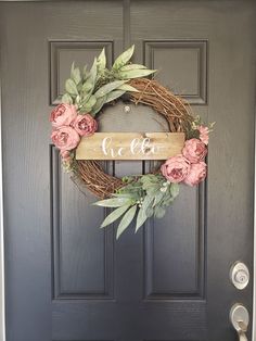 a wreath with the word cia on it and pink flowers is hanging on a door