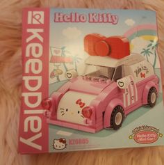 a pink hello kitty toy car on top of a bed