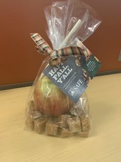 an apple wrapped in cellophane and sitting on top of some pieces of chocolate