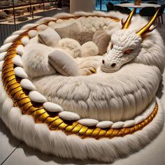 a white and gold dragon bed on display in a room with large windows behind it