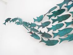 a metal fish sculpture hanging on the side of a wall