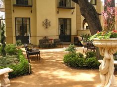 an outdoor courtyard with benches and tables in front of a building that has several balconies on the second floor