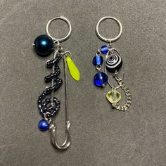 two key chains with charms attached to them on a gray surface, one has a hook and the other is a fish hook