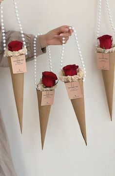 three cones with roses attached to them are hanging on the wall and some pearls are strung around