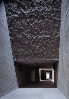 an empty concrete tunnel with light coming through the opening in the wall and cement flooring