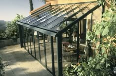 a house that has a glass roof and some plants on the outside side of it