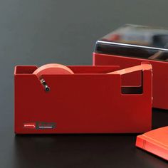 two red boxes sitting next to each other on top of a black table with a cell phone in the background