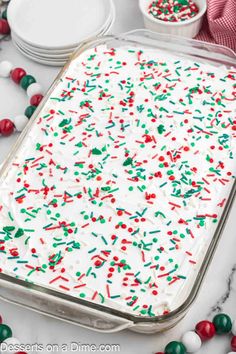 a cake with white frosting and sprinkles in a pan on a table