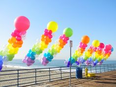 many balloons are floating in the air by the beach