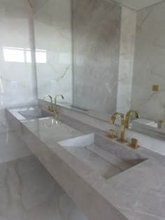 two sinks in a large bathroom with marble counter tops and gold faucet handles