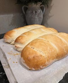 three loaves of bread sitting on top of a paper towel next to a vase