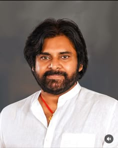 a man with long hair and beard wearing a white shirt is looking at the camera