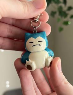 a person holding a small keychain with a cat on it