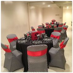 a room filled with black and white tables covered in red and black tablecloths