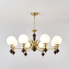 a brass chandelier with five white glass balls hanging from it's center