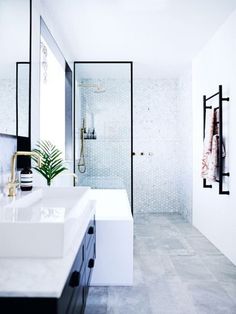 a white bathroom with two sinks and a shower in the back ground, next to a walk - in shower