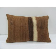 a brown and white striped pillow sitting on top of a bed next to a wall