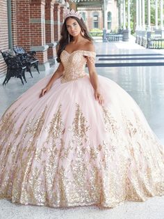 a woman in a pink and gold ball gown posing for the camera with her hand on her hip