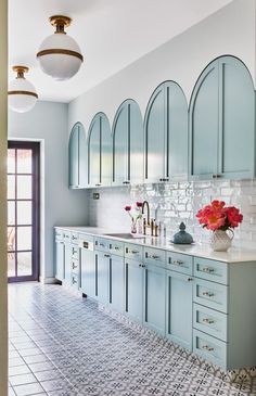 a kitchen with blue cabinets and white tile flooring is pictured in this image, there are vases on the counter