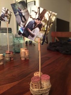 a couple kissing on top of a wooden table next to wine corks and photos