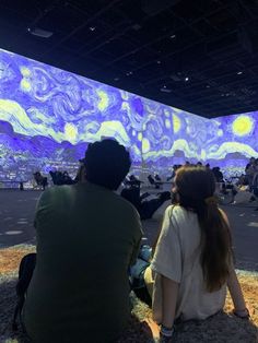 two people sitting on the ground looking at an art project projected in front of them