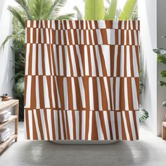 an orange and white striped shower curtain next to a potted plant in a bathroom