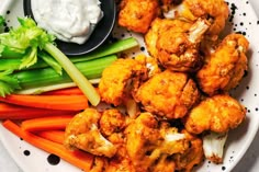 a white plate topped with cauliflower, carrots and celery sticks