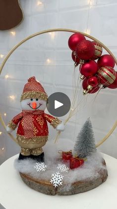 a snowman with red and gold decorations on top of a white table next to a christmas tree