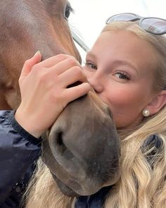 a woman kissing the nose of a horse