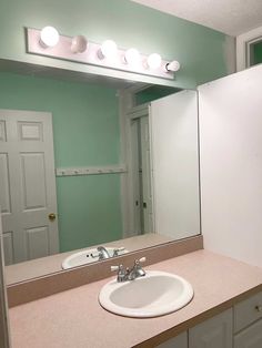 a bathroom sink sitting under a mirror next to a white refrigerator freezer and counter top