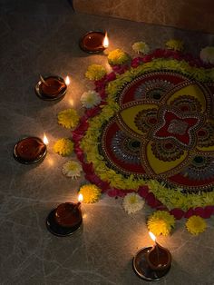 candles are arranged in the shape of a flower and an intricately decorated rangolite