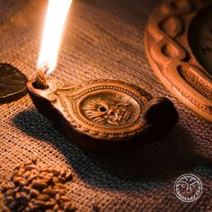 a lit candle sitting on top of a table next to some coins and a clock