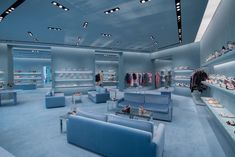 the inside of a clothing store with blue couches and shelves full of shoes on display