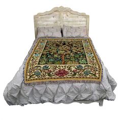 a bed with a white headboard and two pillows on top of it, covered in a multicolored rug