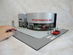 a hand is holding an open model of a car showroom