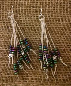 two pairs of earrings are sitting on a piece of fabric with beads hanging from them