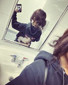 a woman taking a selfie in front of a bathroom mirror with the reflection of her dog