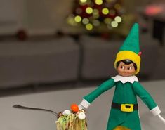 an elf with a green hat and yellow pants is holding a small piece of food