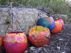 several colorful balls are hanging from a wire on the ground next to a large rock