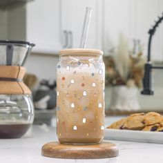 a glass jar with a straw in it sitting on a counter next to some cookies