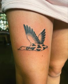 a woman's leg with a tattoo of a bird on the thigh and an arrow in the middle