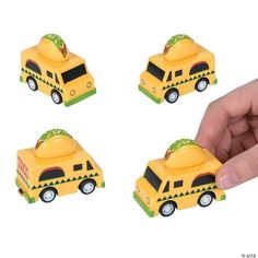 a hand is holding three small yellow toy cars with trees on the top and bottom