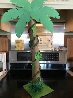 a palm tree made out of toilet paper on top of a kitchen counter with an oven in the background